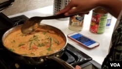 Ariam Mohamed prepares a pasta sauce with chicken and spinach for an iftar during Ramadan. (C. Guensburg/VOA)