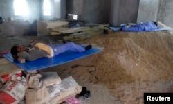 FILE - Construction workers rest during their lunch break in Doha, Qatar.