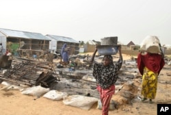 FILE - People walk through the debris at a camp for people displaced following an explosion by Islamist extremists, in Maiduguri, Nigeria, June 8, 2017.