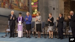 Burmese opposition leader Aung San Suu Kyi, on the podium, second from left, receives standing ovations the Norwegian Nobel Committee her speech at the Peace Nobel Prize lecture at the city hall in Oslo, Saturday, June 16, 2012.