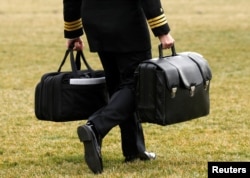 FILE - A military aide, carrying the "football" containing launch codes for nuclear weapons, accompanies U.S. President Donald Trump onto Marine One upon Trump's departure from the White House in Washington, Feb. 3, 2017. Contrary to what Trump tweeted, he has no physical button to initiate a nuclear launch.