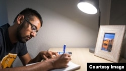 Bhavik Patel, a mechanical engineering senior and peer mentor at Arizona State's community housing center Tooker House, demonstrates use of an Amazon Echo Dot while working on formulas. (Charlie Leight/ASU Now)