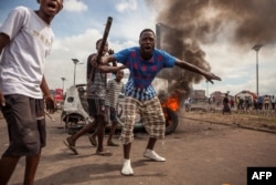 FILE - Demonstrators gather in front of a burning car during an opposition rally in Kinshasa, DRC, Sept. 19, 2016.