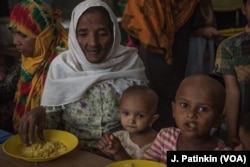 A Rohingya refugee family eats a free lunch given out by Action Against Hunger in Ukhiya, Bangladesh, April 19, 2018. Many families depend on the hot meals handed out by the aid group.