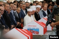 FILE - A guard secures Turkish President Recep Tayyip Erdogan (L) with his machine gun during a funeral service for a victim of the thwarted coup in Istanbul at Fatih mosque in Istanbul, Turkey, July 17, 2016.