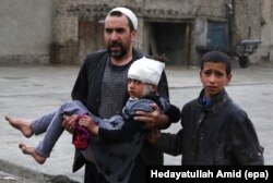 FILE - An Afghan man carries a girl who was injured in a suicide bomb blast that targeted the premises of the Ministry of Defense, in Kabul, Afghanistan, April 19, 2016.