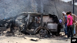 FILE - Yemenis inspect the scene of a car bomb attack that killed a Yemeni senior official in the southern port city of Aden, Yemen, Sunday, Dec. 6, 2015.