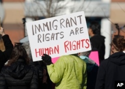 FILE - A supporter holds up a placard during a rally outside the Immigration and Customs Enforcement office in Centennial, Colorado, Feb. 15, 2017.