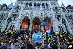FILE - Demonstrators face policemen as they protest against the amendment of the higher education law seen by many as an action aiming at the closure of the Central European University, in Hungary, April 4, 2017.