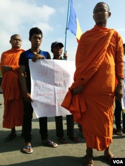 People hold signs that protest a deal signed on Friday that would send refugees from Australian detention centers to Cambodia, near the Australian embassy, in Phnom Penh, Cambodia, Sept. 26, 2014. (Robert Carmichael/VOA
