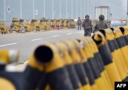 FILE - South Korean soldiers walk by barricades on the road leading to North Korea's Kaesong joint industrial complex at a military checkpoint in the border city of Paju, Aug. 21, 2015.