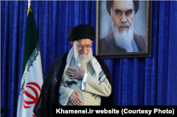 FILE - Iranian Supreme Leader Ayatollah Ali Khamenei gestures to a crowd at a June 4, 2019, ceremony in Tehran marking the 30th anniversary of the death of his predecessor, Ayatollah Ruhollah Khomeini, whose portrait appears behind him.