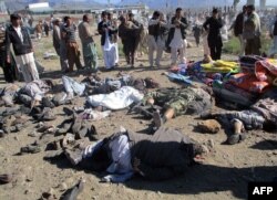 Pakistani men gather beside the bodies of victims of a bomb explosion at a market in Parachinar, the capital of Kurram tribal district, Dec. 13, 2015.