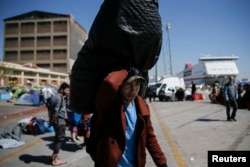A refugee carries his belongings before boarding a bus heading to other parts of the country where refugees and migrants will be accommodated, at the port of Piraeus, near Athens, Greece, March 31, 2016.