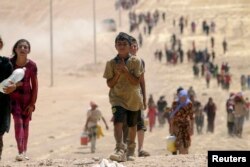 FILE - Children from the minority Yazidi sect, fleeing violence from Islamic State militants Sinjar, Iraq, make their way toward the Syrian border town of Elierbeh, Aug. 10, 2014.