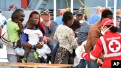 Migrants line up at a Red Cross tent after they disembarked from the Irish Navy vessel LE Niamh at the Messina harbor in Sicily, Italy, Aug. 24, 2015.