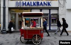 FILE - A street vendor sells roasted chestnuts in front of a branch of Halkbank in central Istanbul, Turkey, Jan. 10, 2018.