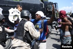 A Haitian National Police officer pushes a protester during a march to demand an investigation into what they say is the alleged misuse of Venezuela-sponsored PetroCaribe funds, in Port-au-Prince, Haiti, Oct. 17, 2018.
