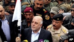 Iraqi Prime Minister Haider al-Abadi, center, raises an Iraqi flag in the city of Ramadi, 70 miles (115 kilometers) west of Baghdad, after it was retaken by the security forces, Dec. 29, 2015.