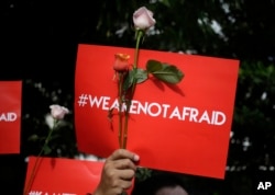 An activist holds a poster during a rally condemning a Jan. 15, 2016 attack, outside a cafe where it took place in Jakarta, Indonesia. Indonesians were shaken but refusing to be cowed a day after a deadly attack that has been claimed by the Islamic State.