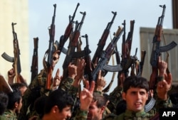 Syrian fighters hold up their weapons during their graduation ceremony near Syria's northeastern city of Hasakah, Jan. 20, 2018.