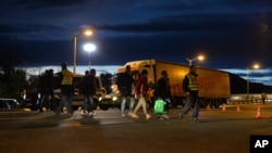 Refugees make their way through a street at the border between Austria and Germany, in Freilassing, southern Germany, Friday, Sept. 18, 2015.