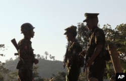 FILE - Three Kachin Independence Army (KIA) soldiers patrol along the bunker at the front line of on a mountain near Laiza, the headquarters of KIA in Kachin State, Myanmar. Nov. 30, 2016.