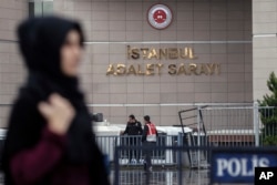 A woman walks along a security barricade outside the main courthouse in Istanbul, Turkey, Oct. 24, 2017.