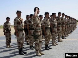 FILE - French troops stand at attention during a handover ceremony of the Timbuktu mission from France to Burkina Faso at Timbuktu airport, April 23, 2013