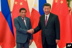 FILE - Philippine President Rodrigo Duterte, left, and Chinese President Xi Jinping pose for photographers on the sidelines of the Belt and Road Forum for International Cooperation at the Great Hall of the People in Beijing, May 15, 2017.