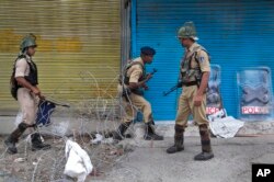 Indian paramilitary soldier cross barbed wire set up as road blockade at a temporary checkpoint during curfew in Srinagar, Indian controlled Kashmir, July 11, 2016.