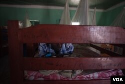 A former Al-Shabab member texts on his phone while lying on his bed in a dormitory at a rehabilitation center for former militants in Baidoa, Somalia, Sept. 17, 2016. (Photo: J. Patinkin/VOA)