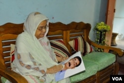 Hajera Khatun, 70, with the photo of her son Sajedul Islam Shumon, who became a victim of enforced disappearance in 2013. (A. Rajjak for VOA)