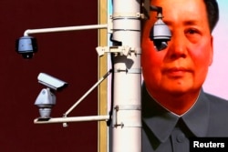 FILE - Security cameras in front of the giant portrait of former Chinese Chairman Mao Zedong on Beijing's Tiananmen Square, Nov. 11, 2012.
