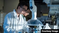 Rice postdoctoral researcher Chuan Xia, left, and chemical and biomolecular engineer Haotian Wang, adjust their electrocatalysis reactor to produce liquid formic acid from carbon dioxide. (Photo by Jeff Fitlow/Rice University's Brown School of Engineering