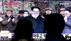 People walk by a TV news program showing North Korean leader Kim Jong Un in Seoul, South Korea, March 4, 2016.