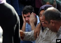 Relatives of people wounded in the explosions in Ankara, react as they wait news for their loved ones outside a hospital, Oct. 10, 2015.