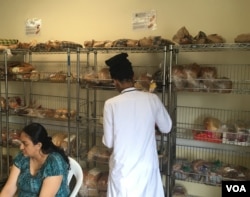 A volunteer at the Arlington Food Assistance Center arranges stacks of bread as a woman waits for free groceries.(VOA/C. Maddux)