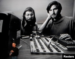 FILE - Apple Chief Executive Officer Steve Jobs stands beneath a photograph of him and Apple-co founder Steve Wozniak from the early days of Apple during the launch of Apple&#39;s new &quot;iPad&quot; tablet computing device in San Francisco, California, Jan. 27, 2010.