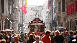 FILE - People walk in central Istanbul&#39;s Istiklal Avenue, the main shopping road of Istanbul, in this photo dated Wednesday, Aug. 22, 2018. Tourists have returned in droves to Turkey, helped this summer by the sharp fall in the value of the Turkish lira following economic uncertainty and a rift with the United States.