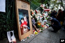 FILE - A woman lights candles to pay respect in front of the Bataclan concert hall, site of a terror attack nearly three years ago, in Paris, France Nov. 13, 2016. The country, since 2015, has been battered by a series of attacks with the loss of over 240 lives.