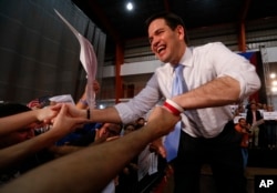 FILE - Republican presidential candidate, Sen. Marco Rubio, R-Fla., shakes hands at a rally in Toa Baja, Puerto Rico, March 5, 2016. The Republican primary will be held on the island nation Sunday.