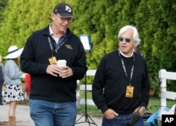 Improbable trainer Bob Baffert, right, and co-owner, Elliott Walden, walk to the track during training for Saturday's Preakness horse race at Pimlico race track in Baltimore, May 17, 2019.