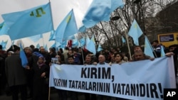 Turks of Crimean Tatar origin waves Crimean flags and hold a banner that reads " Crimea is the homeland of Crimean Tatars " as they demonstrate to protest against Russia's military intervention in Crimea, Ukraine, in Ankara, Turkey, Sunday, March 2, 2014.