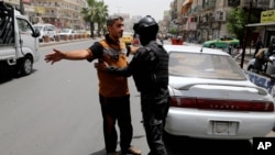 With tightened security measures, an Iraqi federal policeman conducts a search at aBaghdad checkpoint on June. 11, 2014.