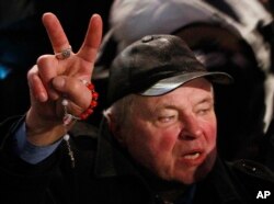 A supporter of the government holds a rosary and shows a victory sign during the demonstration organized by the ruling Polish party Law and Justice in Warsaw, Tuesday, Dec. 13, 2016.