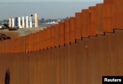FILE - Prototypes for President Donald Trump's border wall are seen behind a border fence between Mexico and the United States, in Tijuana, Mexico, Jan. 7, 2019.