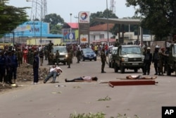 FILE - The bodies of people killed during anti-Kabila protests lie in the street as Congolese troops stand by, in Kinshasa, DRC, Sept. 19, 2016.
