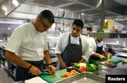Chef Atul Kochhar (L) slices tomatoes at his Benares restaurant in Mayfair, central London, Jan. 21, 2015.