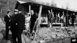File - President Lyndon B. Johnson and his wife, Lady Bird, center left, leave home of Tom Fletcher, a father of eight who told Johnson he'd been out of work for nearly two years, Inez, Kentucky, April 24, 1964.